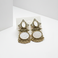 Pair of ornate earrings with white centers on a white background