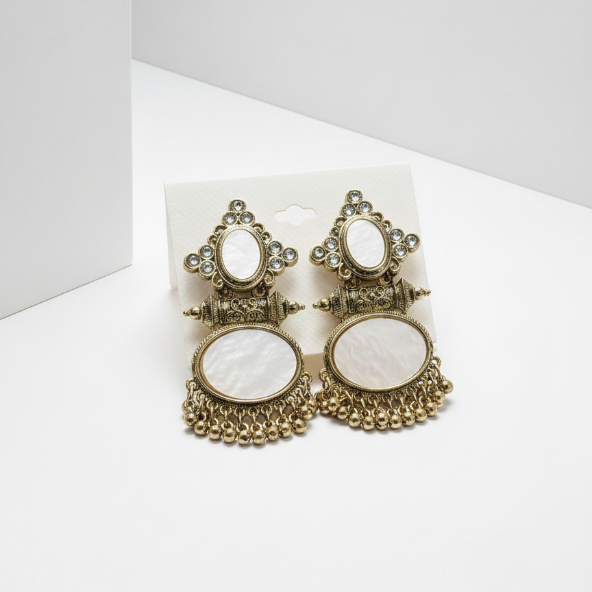 Pair of ornate earrings with white centers on a white background